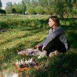 woman playing chess on lawn in park