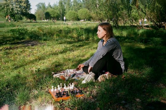 woman playing chess on lawn in park