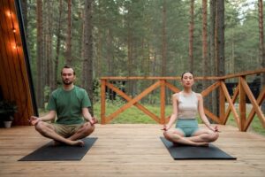 couple sitting on yoga mats in the forest