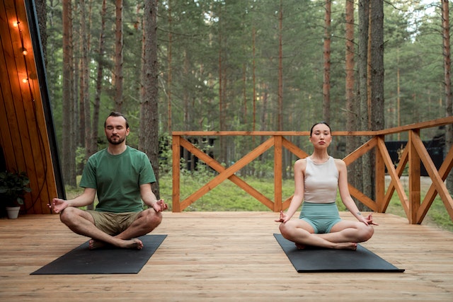 couple sitting on yoga mats in the forest