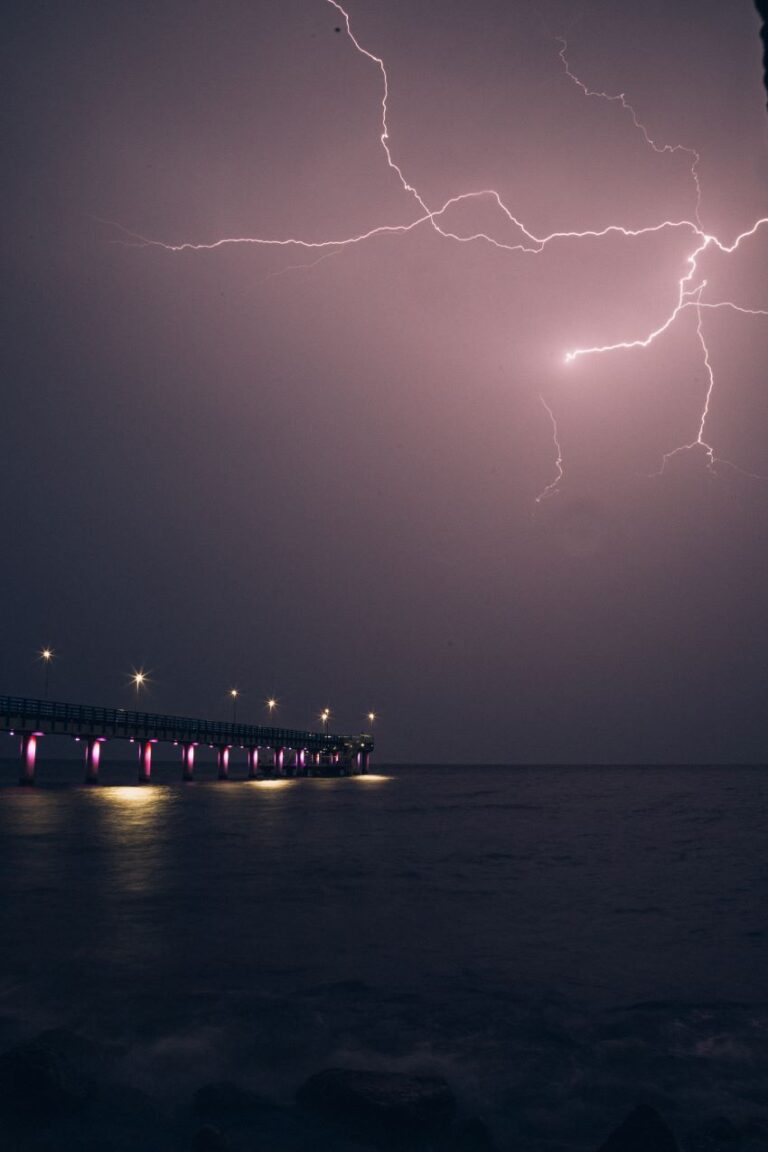 lightning flashes over a pier at night
