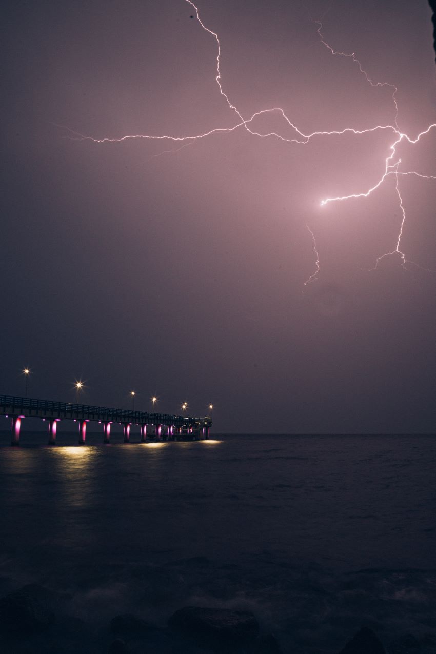 lightning flashes over a pier at night