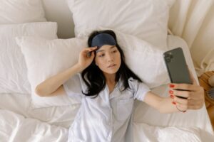 woman in pajamas lying on bed taking-selfie
