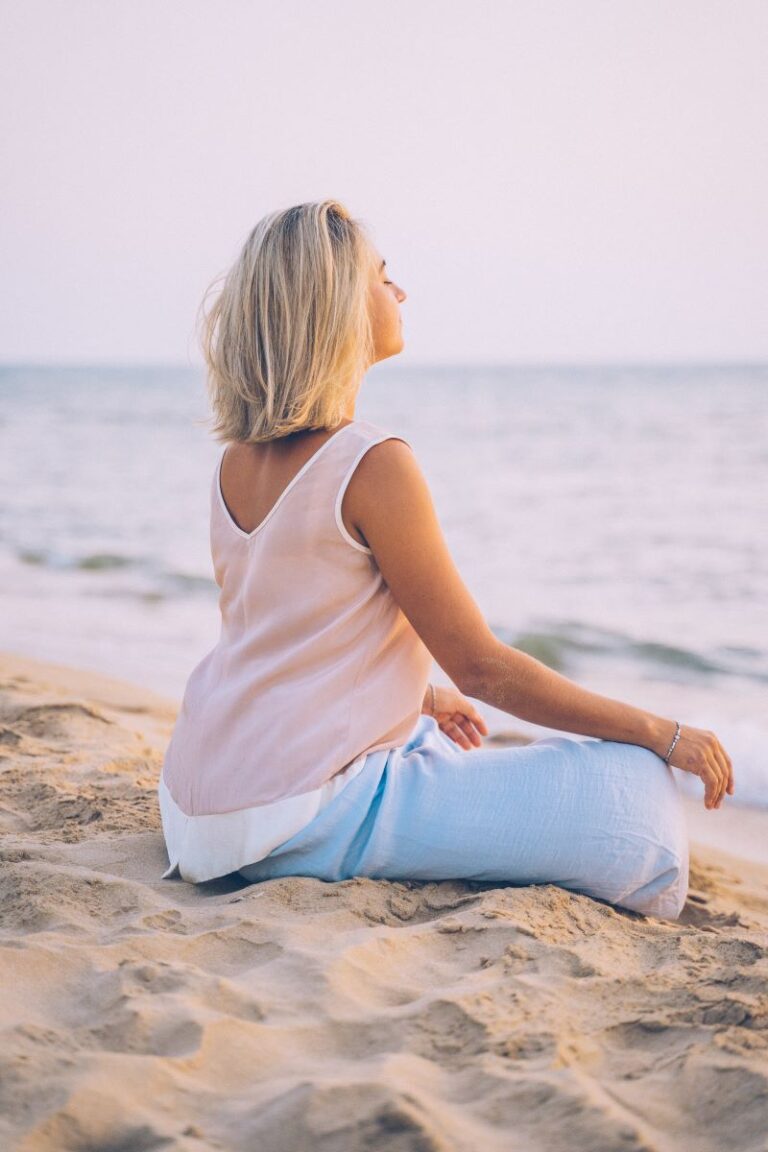 a woman meditating at the beach
