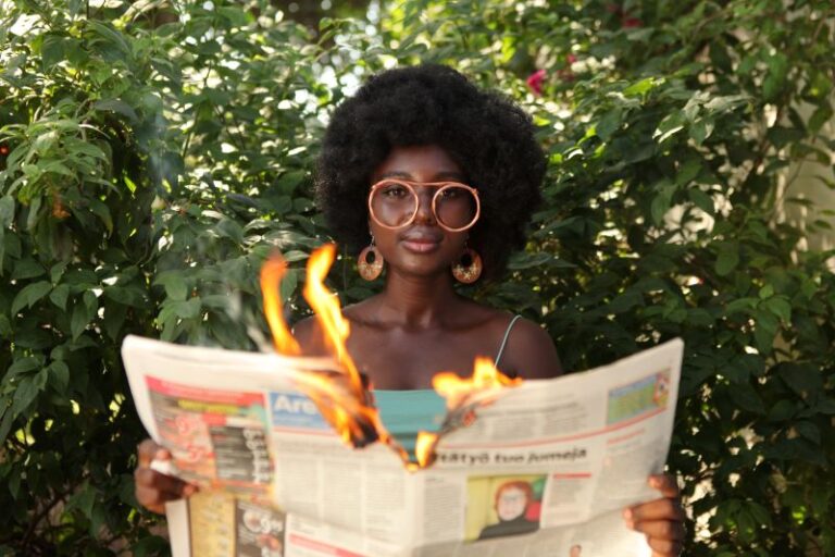 trendy woman burning newspaper in garden