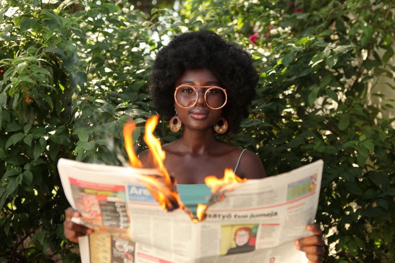 trendy woman burning newspaper in garden