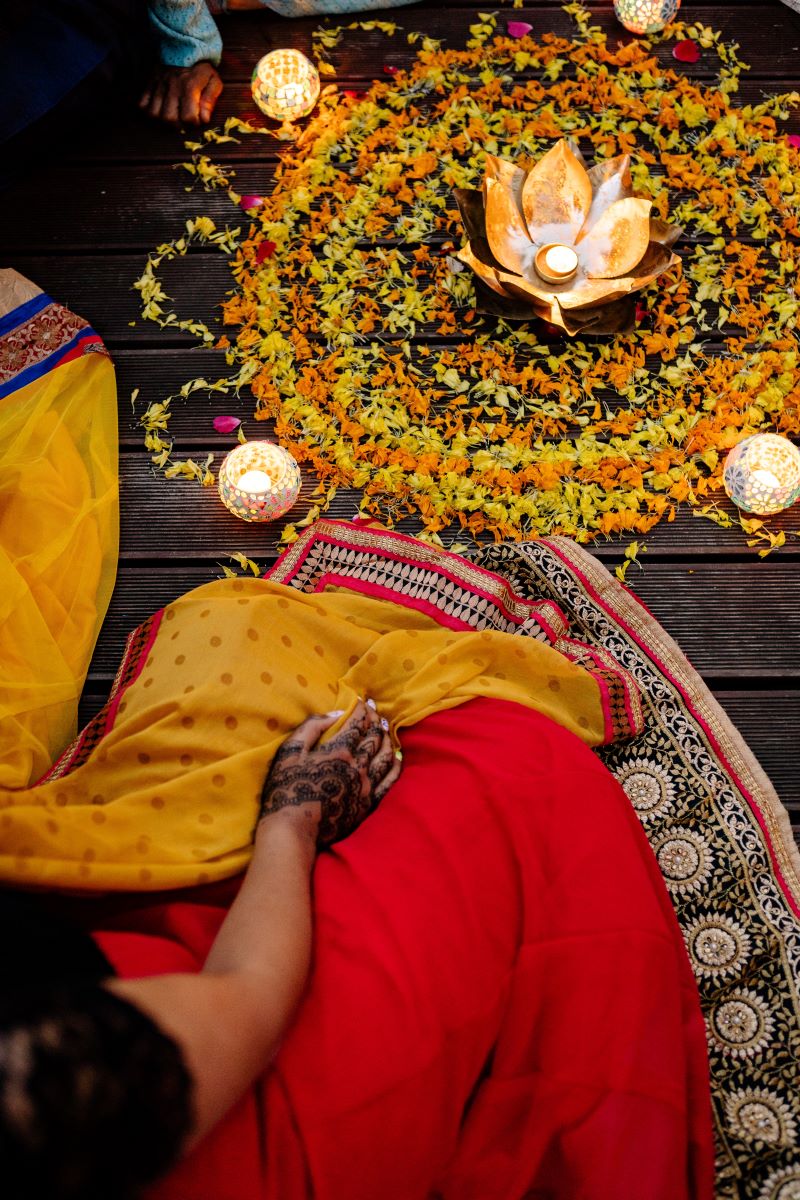 person sitting in front of a flower arrangement wearing a traditional clothes during Diwali