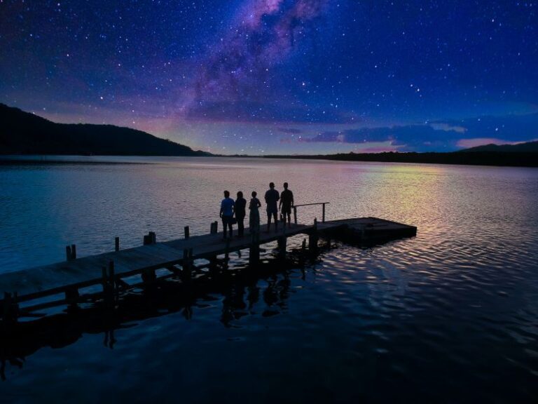 unrecognizable people standing on pier under starry night