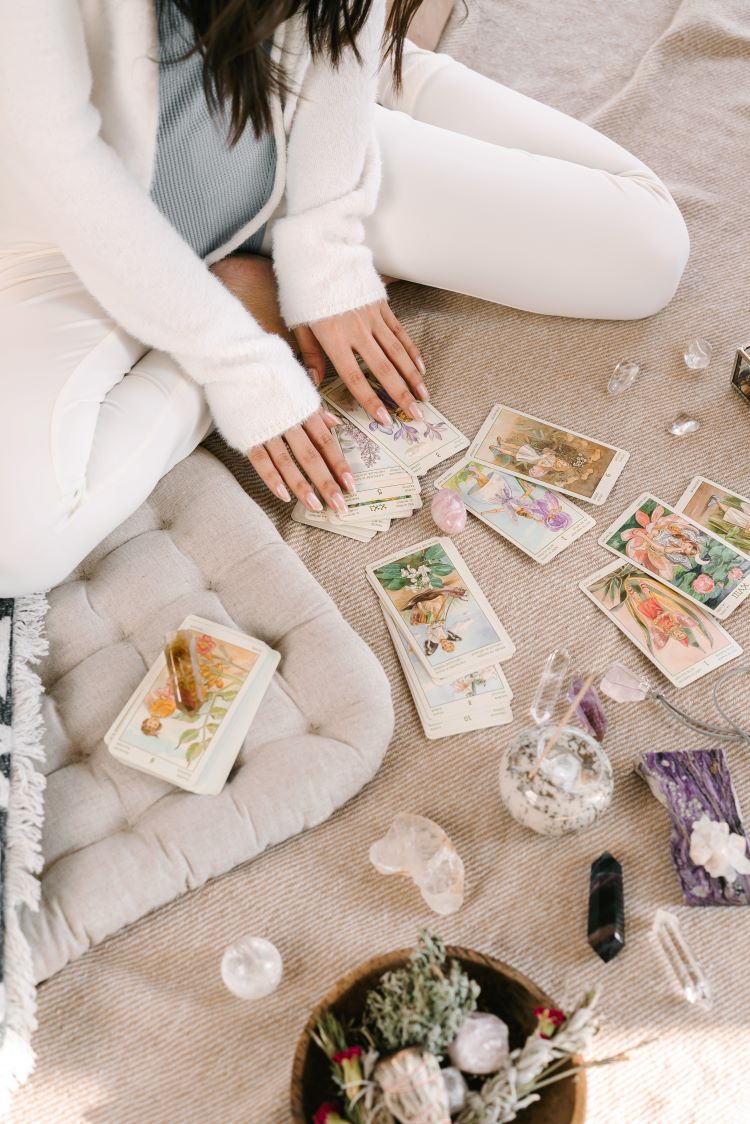person doing tarot while touching a pink crystal